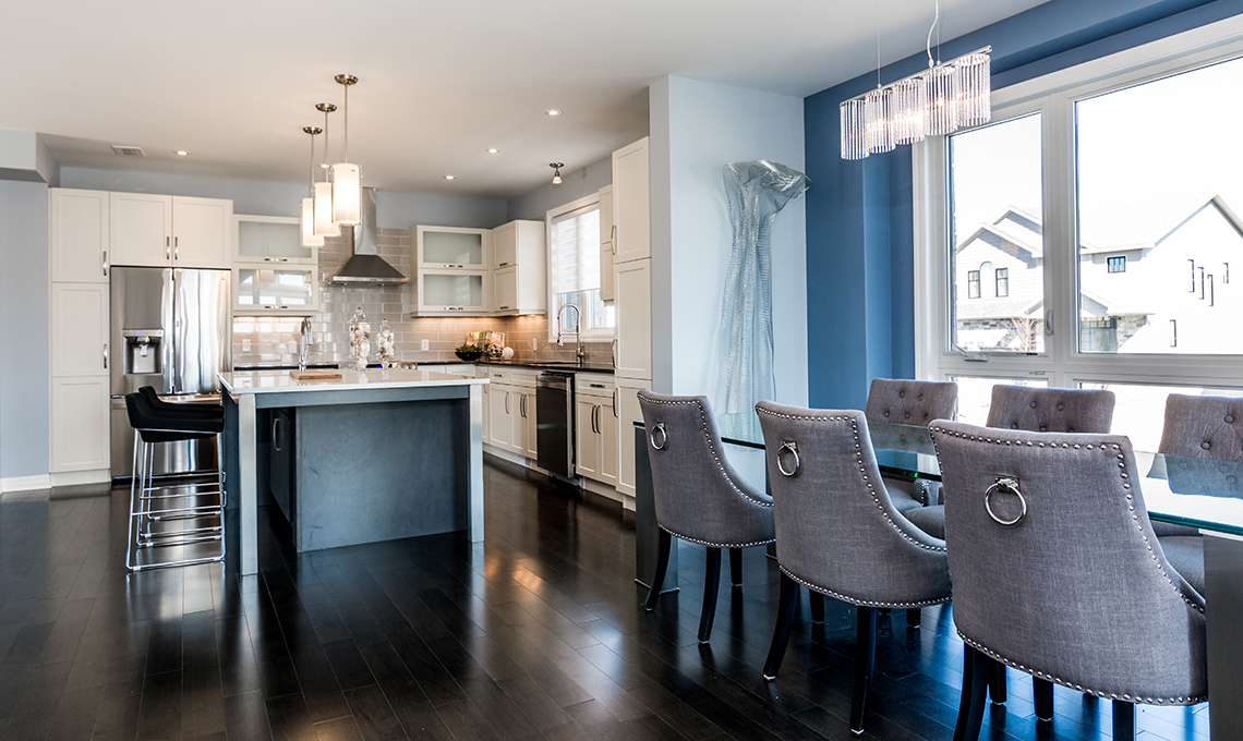 A stylish and bright kitchen with blue walls and white counters and chairs.