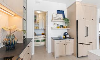 A brightly lit kitchen with a door leading into the pantry closet.